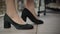 Close-up of female Caucasian feet in black high-heels. Unrecognizable woman trying on shoes in shop. Shopping and