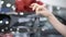 Close-up of female Caucasian hand holding car keys with blurred black vehicle standing at the background in dealership