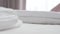 Close-up of female Caucasian hands putting white towels on bed and straightening them. Unrecognizable hotel maid