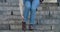 Close-up of female Caucasian legs stepping down the stairs and stopping because of ankle pain. Woman in jeans and brown