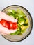 Close up of female chef hand putting Feta cheese cubes on greek vegan tomato salad with olives and lettuce leaves. The concept of