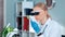 Close-up of female chemistry research scientist in magnifying eyeglasses looking on sample