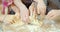 Close up of female and children`s hands kneading dough together in the kitchen