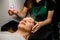 close-up of female client and beautician moisturizes her face with steam from portable humidifier