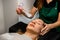 close-up of female client and beautician neatly moisturizes her face with steam from portable humidifier