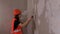 Close up of female construction worker, with spatula flattens wall in room. Young woman sanding wall and preparing for