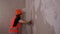 Close up of female construction worker, with spatula flattens wall in room. Young woman sanding wall and preparing for