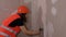 Close up of female construction worker, with spatula flattens wall in room. Young woman sanding wall and preparing for