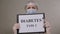 Close-up of female doctor in a uniform holding a sign that says TYPE 2 DIABETES.