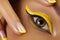 Close-up Female Eye with bright yellow Eyeliner Makeup. Neon Disco make-up and Fashion Manicure. Summer beauty style