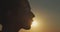 Close up female face profile silhouetted on evening sky setting sun slow motion. Happy woman kissing sun on nature