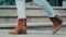 Close-up of female feet legs unrecognizable lady walking along sidewalk in city stepping in street. Cropped view of