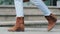Close-up of female feet legs walking along sidewalk in city. Cropped view of unrecognizable woman wearing blue jeans and