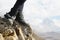 Close-up of female feet in vintage boots stand on a rock in the mountains against the background of an epic landscape of