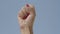 Close-up of female fist raising up at the background of clear blue sky. Unrecognizable woman showing liberty gesture