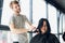 Close up. Female hairdresser straighten brown hair to woman using hair iron in beauty salon. Female stylist makes