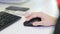 Close-up of female hand on black mouse. Woman`s hand using cordless mouse on white table. Close up portrait of the hands