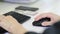 Close-up of female hand on black mouse. Woman`s hand using cordless mouse on white table. Close up portrait of the hands