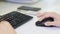 Close-up of female hand on black mouse. Woman`s hand using cordless mouse on white table. Close up portrait of the hands