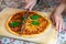 Close-up female hand cutting baked tasty hot homemade italian Margarita pizza on wooden cutboard and table with regular