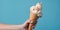 Close-up of female hand holding ice cream cone on blue background