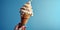 Close-up of female hand holding ice cream cone on blue background