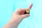 Close-up female hand holding a tube with new pink, peach lipstick on a blue background, wants to do makeup, concept of decorative