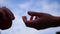 Close-up female hand holds red ripe apple and male hand takes it against blue sky