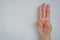 Close-up of female hand showing three fingers  on grey background. Side view close up details.