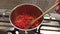 Close up of female hand is stirring tomatoes stew in a saucepan for tomato sauce