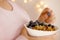 close-up female hand takes berries on blurred background with bokeh, healthy food white cup, oatmeal, blueberries, nuts, almonds,
