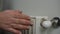 Close-up female hand turning home radiator valve turning on heating equipment. Closeup unrecognizable Caucasian young