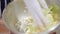 Close-up of female hand in white glove mixing healthful vegetable salad in metal bowl. Unrecognizable cook working in