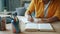 Close-up of female hand writing in notebook while woman reading book at table