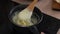 close-up of female hands boil porridge in a saucepan, stir with a wooden spoon and put a piece of butter