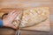 Close-up female hands cut into small pieces freshly cooked delicious fresh handmade bread, which lies on a wooden board.