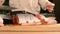 Close-up of female hands are cutting with a knife a large salmon on a wooden table of home cooking