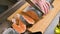 Close-up of female hands are cutting with a knife a large salmon on a wooden table of home cooking