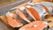 Close-up of female hands are cutting with a knife a large salmon on a wooden table of home cooking