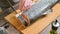 Close-up of female hands are cutting with a knife a large salmon on a wooden table of home cooking