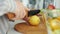 Close-up of female hands cutting lemon with knife cooking salad in kitchen