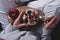 Close-up of female hands with glass bowl with oatmeal and berries and Apple