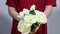 Close up female hands holding colorful roses bouquet. Woman hands touching rose buds leafs, white knitted sweater background