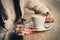 Close-up female hands holding cup with coffee cappuccino with foam with pattern heart. Perfect red gel polish manicure. Wood