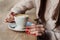 Close-up female hands holding cup with coffee cappuccino with foam with pattern heart. Perfect red gel polish manicure. Wood