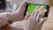 Close-up of female hands holding phone horizontal with green screen. Stock footage. Female freelancer working with phone