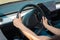 Close up of female hands holding the steering wheel during driving lesson. Driving test, driver courses, exam concept