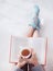 Close up of female hands holding teacup in front of opened book