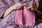 Close up of female hands knitting  cotton pink tape