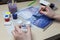 A close-up of female hands over a painted picture holding a brush and a cover for watercolors on which the colors are mixed next